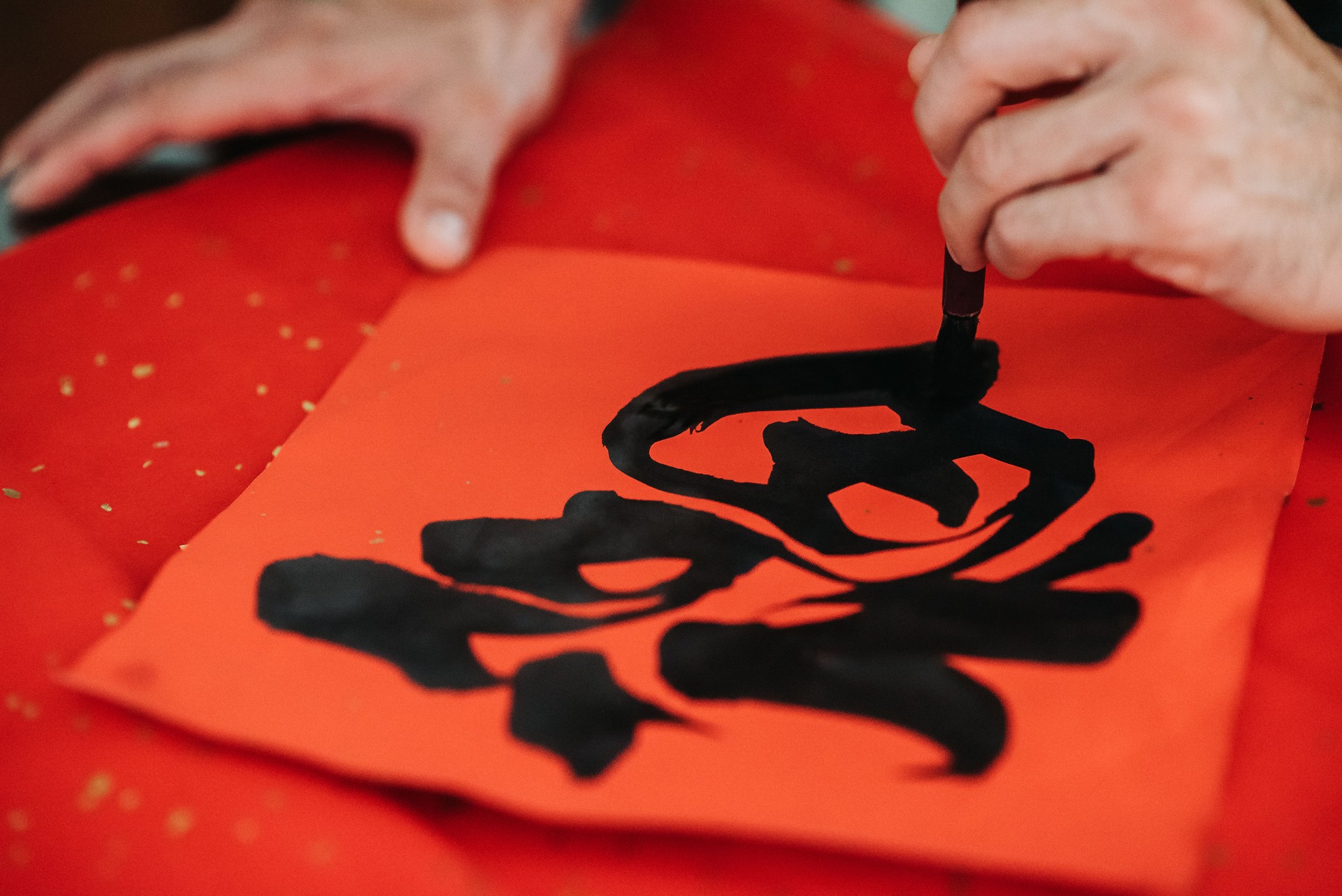 Hand writing chinese calligraphy characters on red colour paper during chinese new year's eve